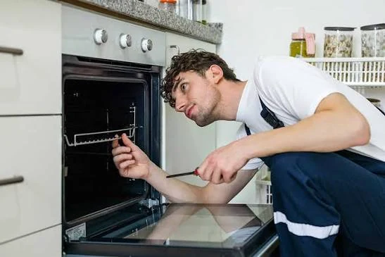 Technician inspecting a built-in oven with a screwdriver